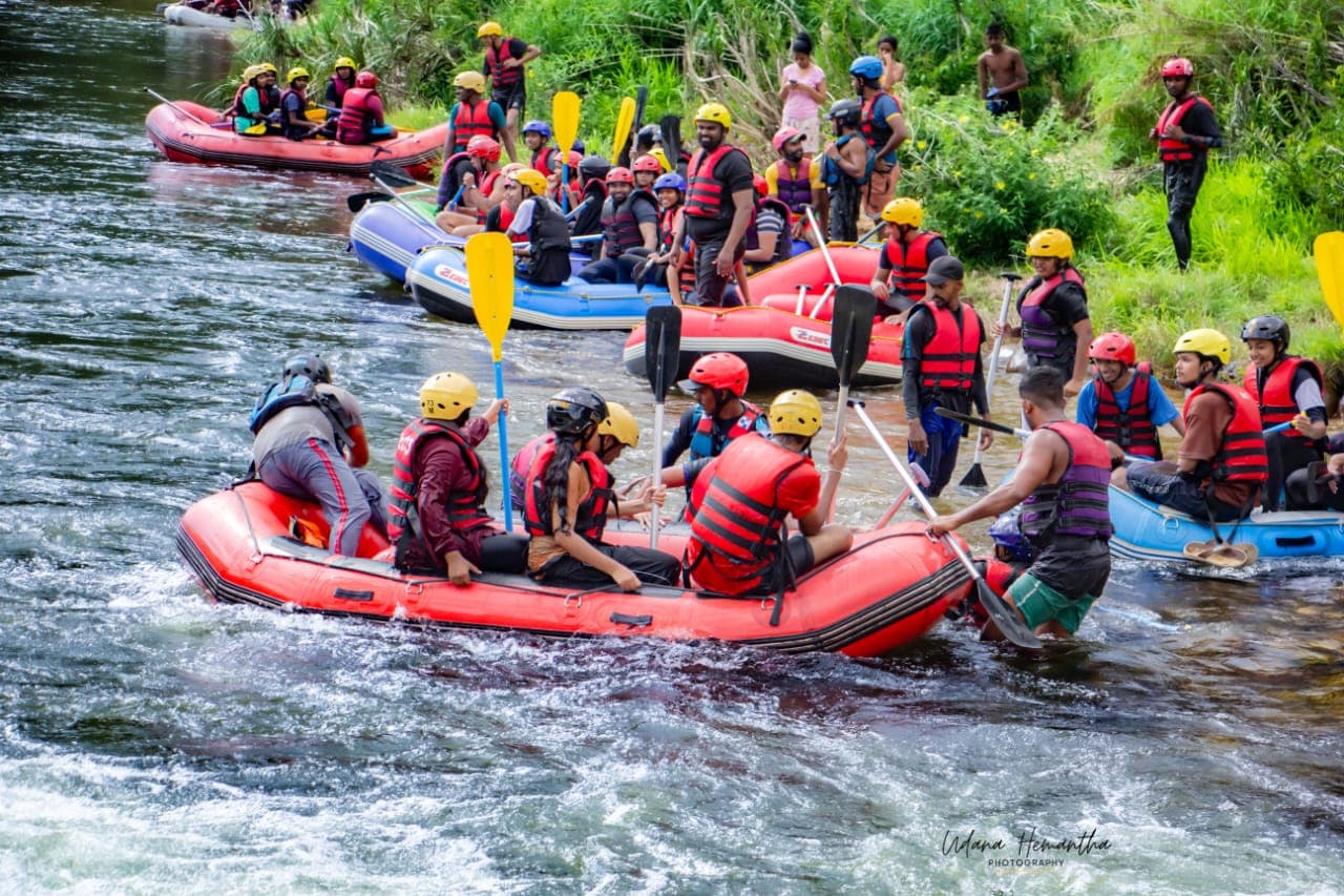 More than thirty colleagues in helmets and buoyancy aids gathered around a fleet of rafts on the Kelani River at Kitulgala