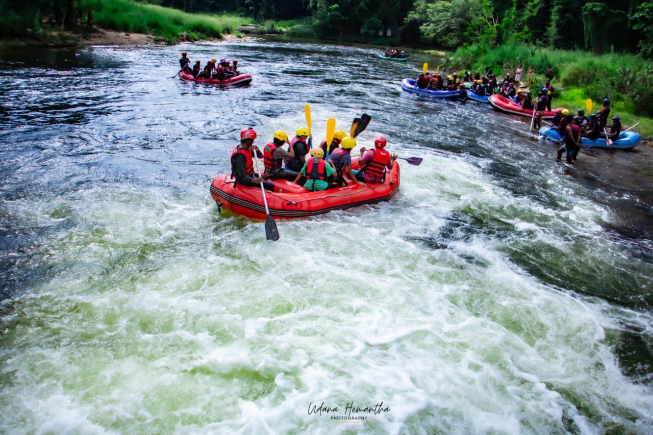 Multiple rafts carrying a big group around a bend on the Kelani River at Kitulgala