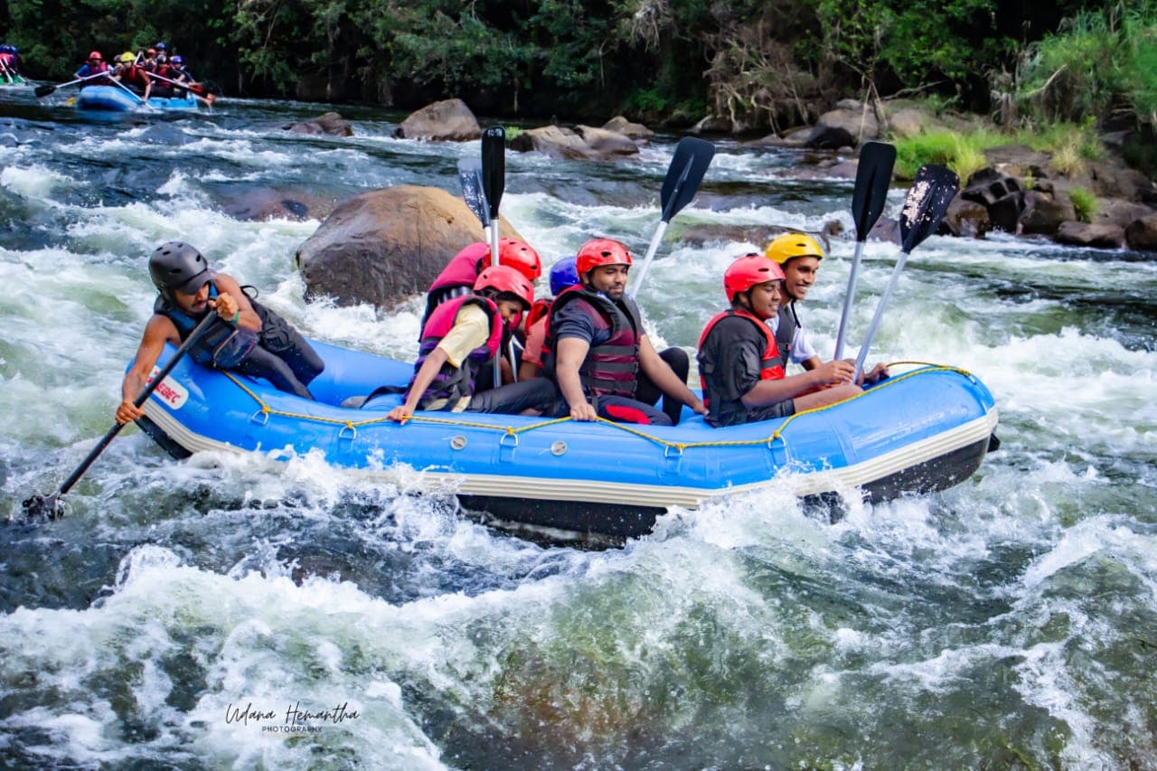 A rafting team of about twelve paddling together through the rapids at Kitulgala, laughing