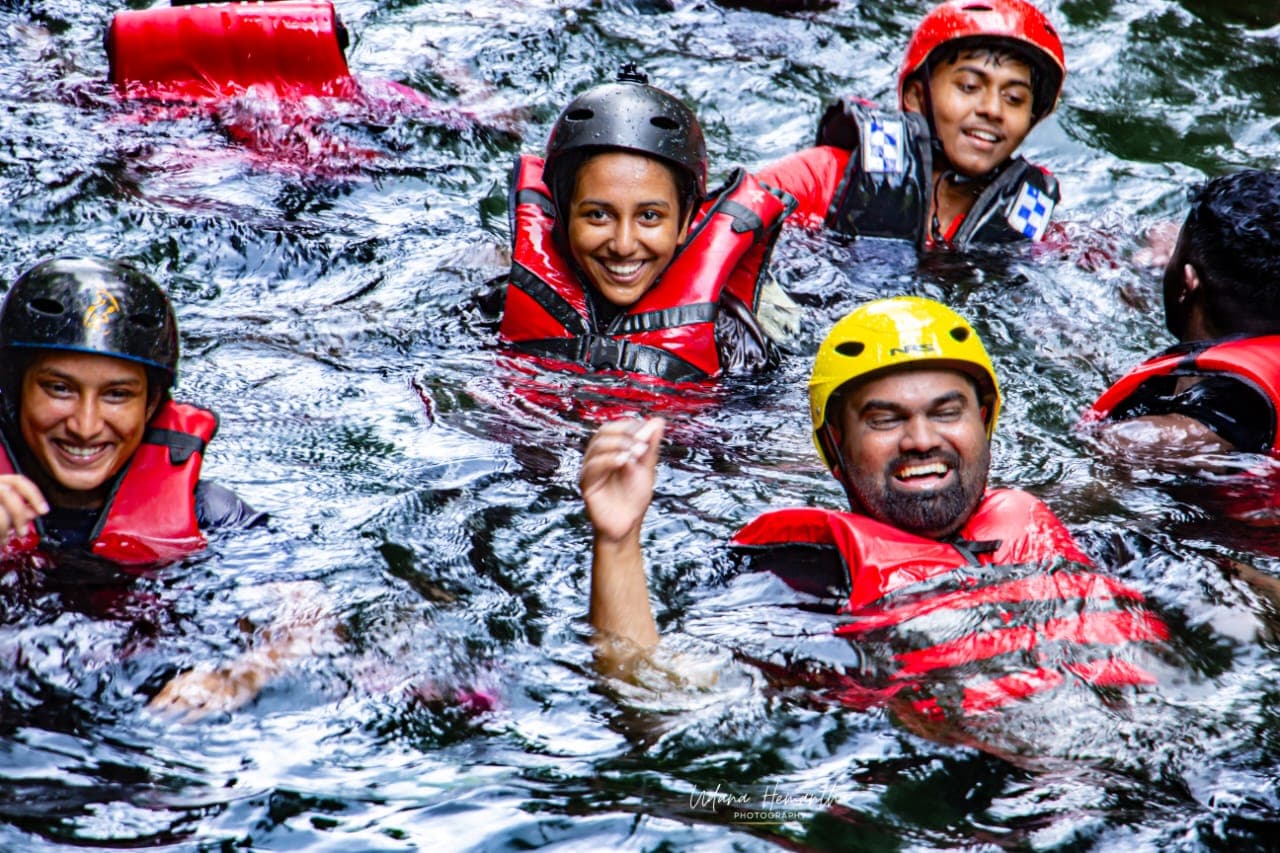 A small group of colleagues laughing together in the river after completing their Kitulgala adventure day