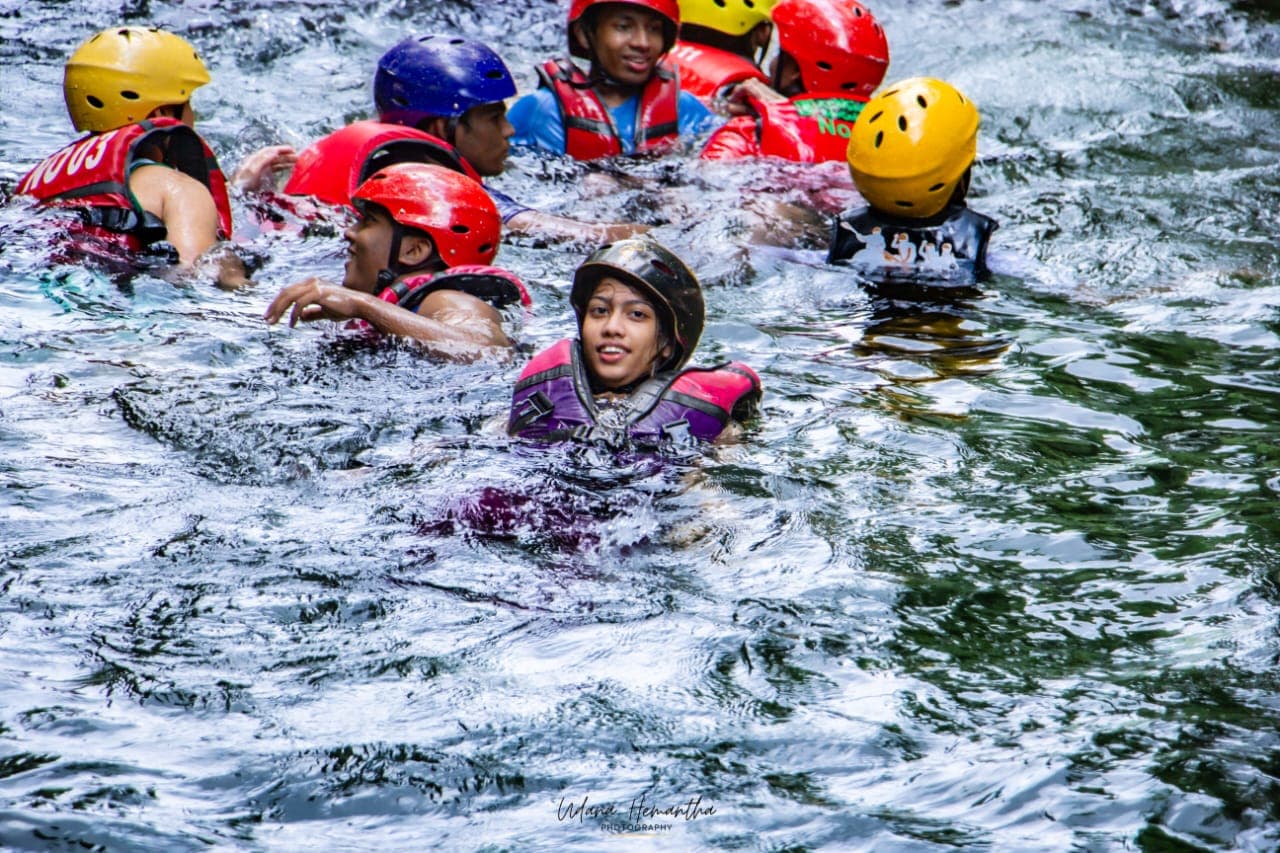 A small supervised group of students swimming together in a calm stretch of the Kelani River at Kitulgala