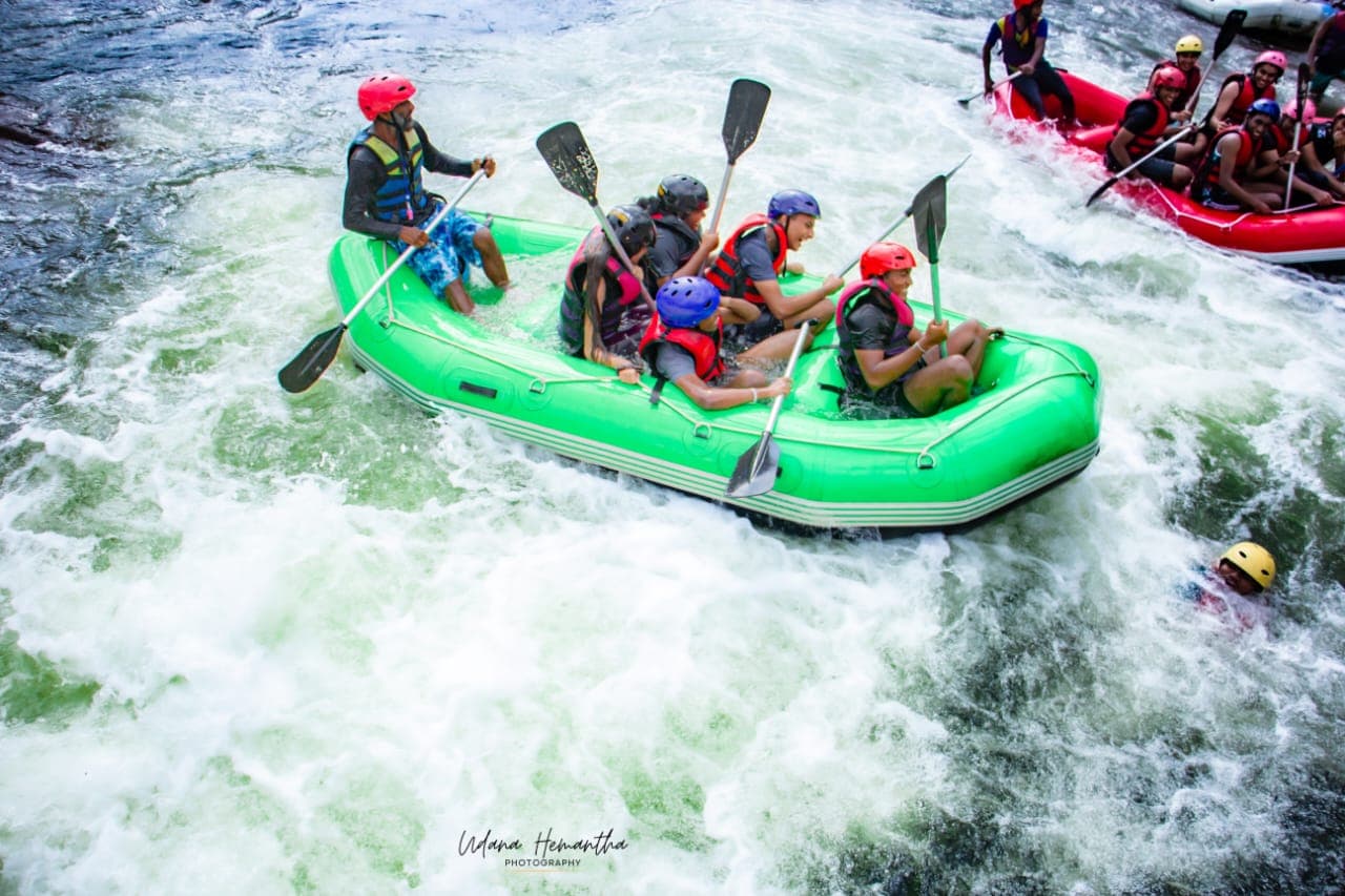 Two rafts carrying a dozen paddlers through a grade two rapid on the Kelani River at Kitulgala